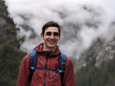 A headshot of Victor Vescu with mountains and clouds behind.